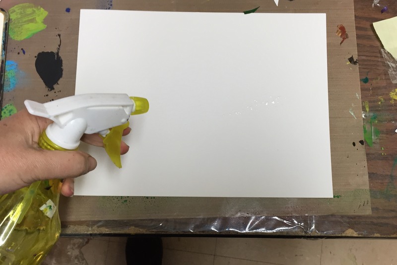 spraying watercolor paper with water