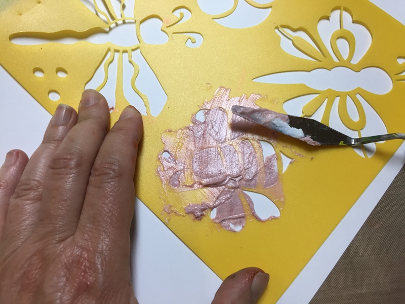 pushing tinted gel medium through a bee stencils